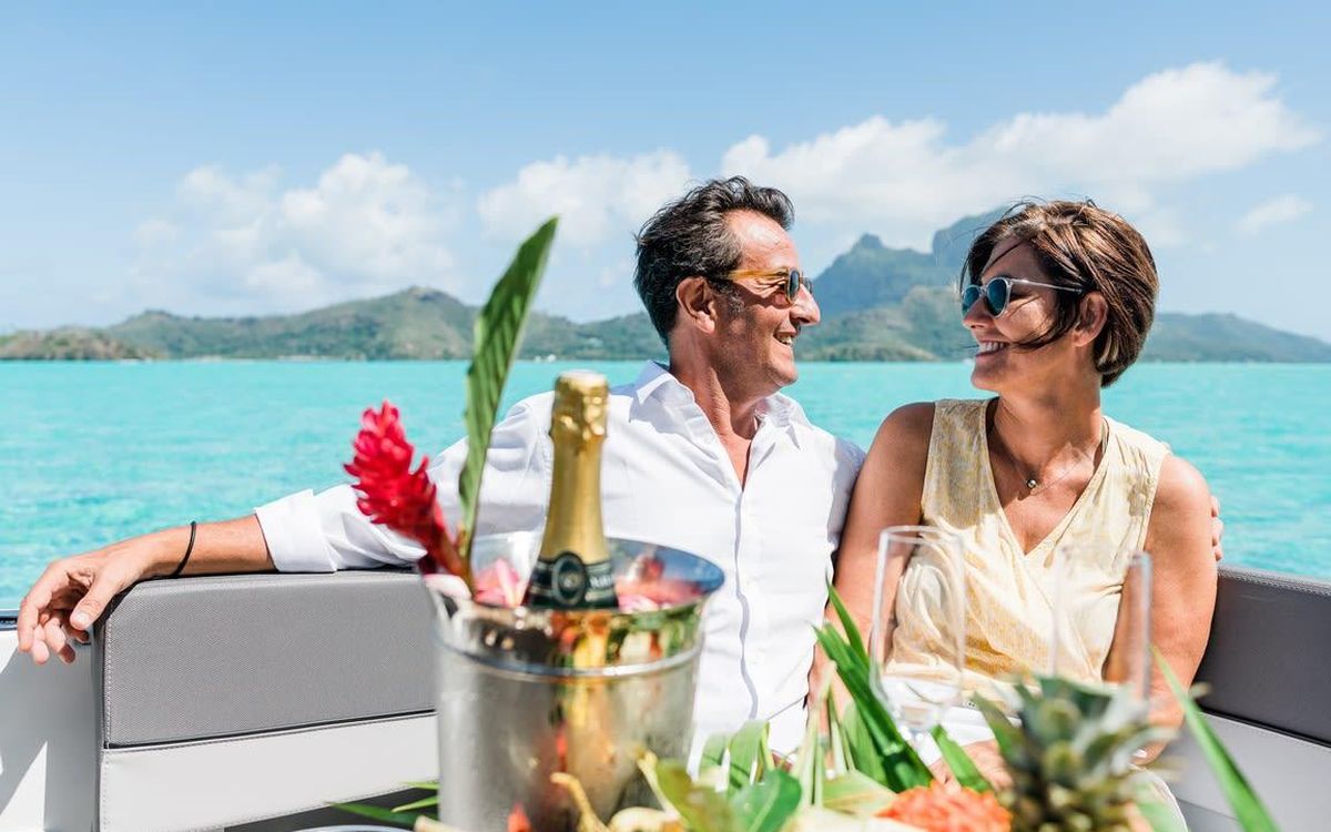 Couple au champagne à bord d'un bateau privé, fleurs de gingembre et mont Otemanu