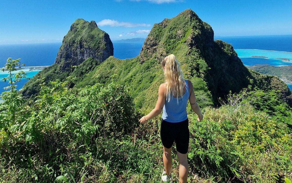 Randonneuse sur la crête face aux pitons de Bora Bora, le lagon en contrebas