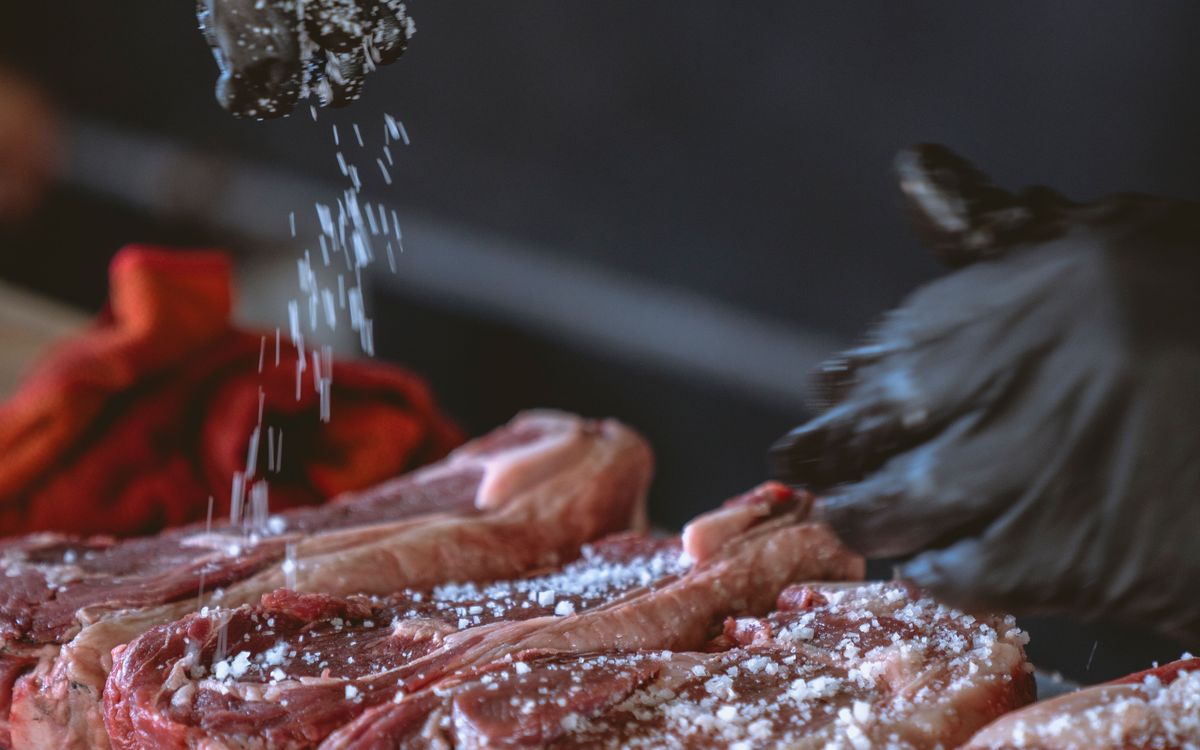 Chef assaisonnant de belles pièces de viande avant livraison